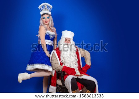 Positive Santa Claus in a red coat and Snow Maiden in a blue suit posing on a red background