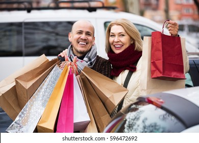 Positive Senior Couple With Shopping Bags Near Parked Car