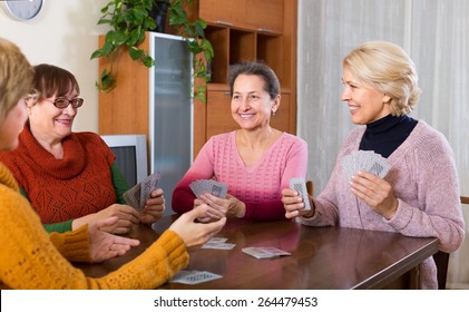 Positive senior female friends enjoy  bridge at home