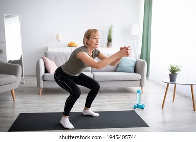 Positive Senior Lady Doing Squats On Domestic Workout In Living Room, Free Space. Fit Mature Woman Leading Active Lifestyle, Losing Weight, Staying In Good Shape At Home During Coronavirus Quarantine