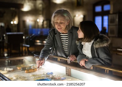 Positive Senior Woman And Emotional Inquisitive Tween Girl Observing With Interest Arts And Crafts On Exhibition In Art Gallery