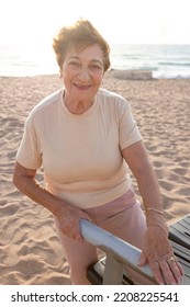 Positive Senior Woman Goes In For Sports Outdoors. Pensioner Does Fitness On Beach Using Exercise Equipment. Concept Of Physical Activity In Old Age, Health, Work Out, Healthy Lifestyle. Woman 80+