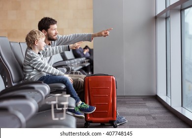 Positive Smiling Boy And His Father Waiting At The Airport For Plane Departure And Pointing With Fingers At Something, Vacation And Travel Concept