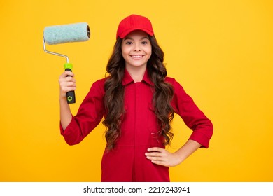 Positive And Smiling Builder In Building Uniform And Cap. Painter Painting With Paint Roller. Worker Isolated On Yellow Background. Kids Renovation Concept.