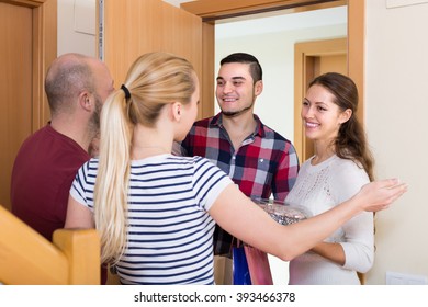 Positive smiling guests with presents and cake standing in doorway. Focus on girl