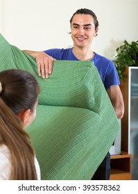 Positive Smiling Man And Woman Moving Furniture In Room
