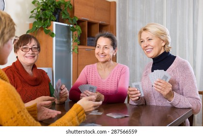 Positive smiling senior women playing cards at home