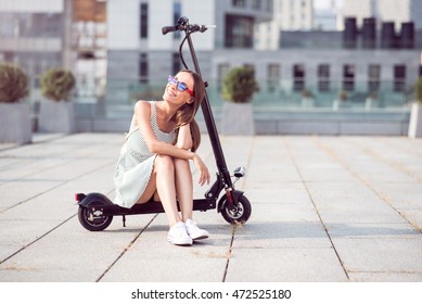 Positive Smiling Woman Riding A Kick Scooter