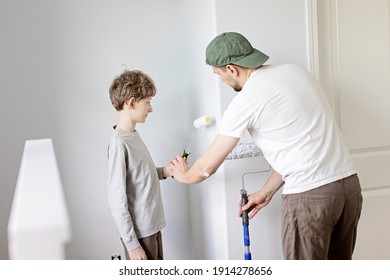 positiver lächelender kleiner Junge, der seinem Vater hilft, zu Hause Wände zu malen, Familienrenovierungsprojekt