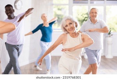 Positive sporty senior woman participating group dance class, practicing modern vigorous energetic dance movements - Powered by Shutterstock