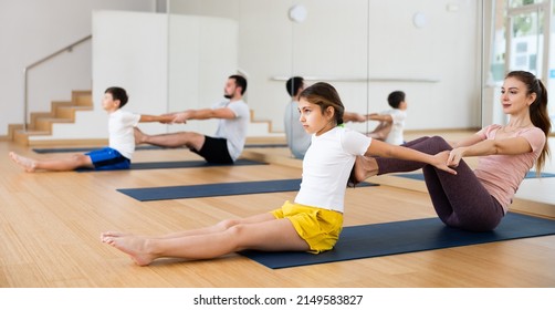 Positive Sporty Teen Girl Practicing Partner Yoga In Pair With Mother During Training With Family In Fitness Center..