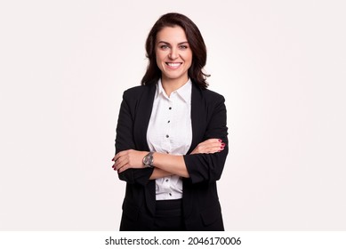 Una exitosa directora ejecutiva de mediana edad con traje negro elegante y reloj de pulsera que cruza los brazos y mira la cámara contra fondo blanco