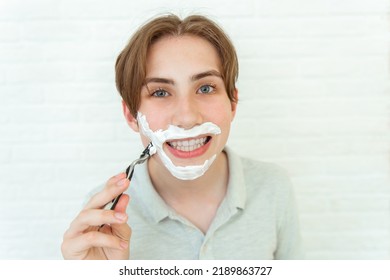 Positive Teen Boy In The Bath With Shaving Cream On His Face And Shaving Razor