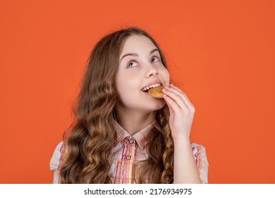 Positive Teen Girl Eating Oatmeal Cookies On Orange Background