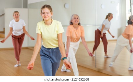 Positive Teen Girl With Family Doing Aerobics Exercises With Group Of People In Dance Center