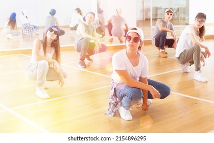 Positive Teen Girls And Boys Hip Hop Dancers Squatting During Group Dance Workout