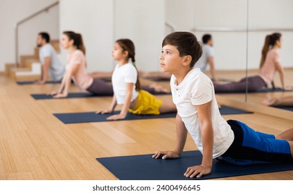 Positive teenage boy performing yoga exercises with family at yoga studio - Powered by Shutterstock