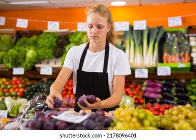 Positive Teenage Girl At Her First Job, Selling Sweet Plums In Vegetable Store