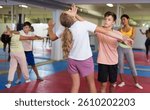 Positive teenager kids in pair exercising self-defense movements during group class