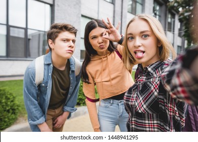positive teenagers taking selfie and showing ok gesture outside 