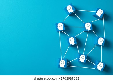 Positive thinking and mental health concept. Network of blue blocks with smiling face icons symbolizing happiness, customer satisfaction, and social connection on a blue background with copy space.