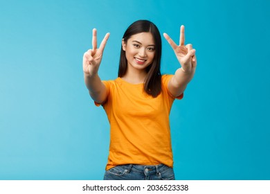 Positive upbeat cute asian girl believe win, aim success extend hands show victory, peace sign smiling broadly, have happy enthusiastic mood, spend carefree vacation travel abroad value pacifism