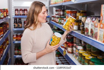 Positive woman customer choosing pickle goods in the food store