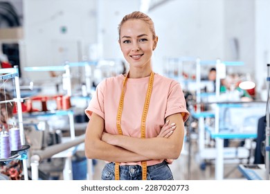 positive woman dressmaker standing in textile factory at workshop, attractive tailor after work stand posing, looking at camera smiling. female use measuring tape for sewing and making garments - Powered by Shutterstock