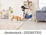 Positive woman feeding dog from a bowl with pet food at home. The domestic pet happily eats, showcasing the bond between the owner and animal friend in a peaceful home environment.