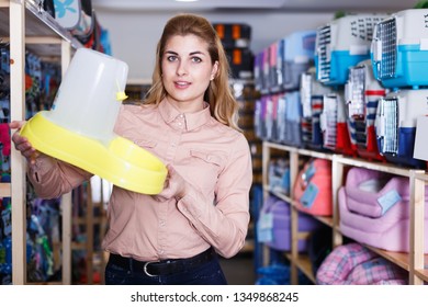 Positive Woman In Pet Store Suggesting Pet Food Dispenser