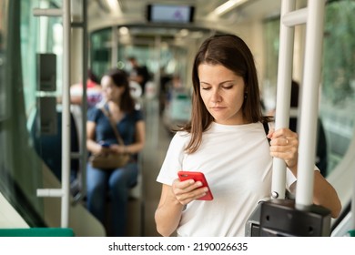 Positive woman reading from mobile phone screen in the cabin of bus or tram. High quality photo - Shutterstock ID 2190026635