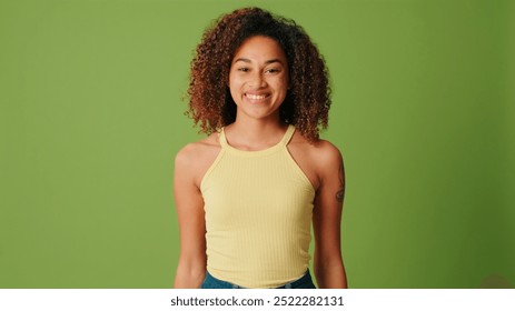 The positive woman smiles shyly to camera on green screen background - Powered by Shutterstock