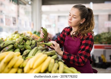 Positive Woman Store Employee Displaying Assortment Of Bananas At Fruit Department In Supermarket