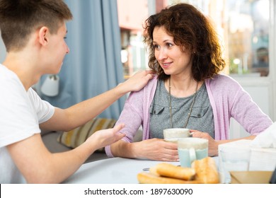 Positive Woman With Teen Son Enjoying Time At Home, Having Friendly Conversation