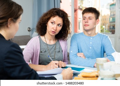 Positive woman with teenager boy discussing documents with financial adviser