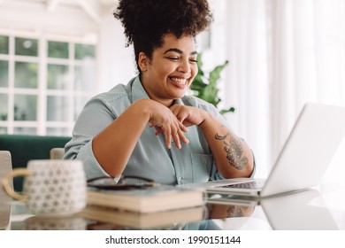 Positive woman video calling using laptop. Businesswoman teleconferencing on laptop while working from home.