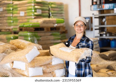 Positive woman worker loading sacks at warehouse store