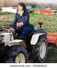 Positive Woman Working On Small Farm Tractor. High Quality Photo