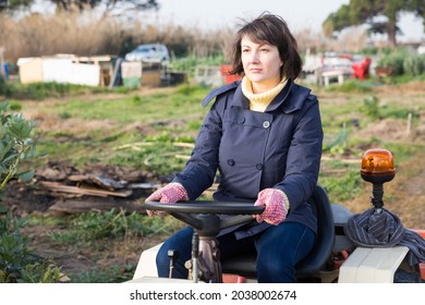 Positive Woman Working On Small Farm Tractor. High Quality Photo