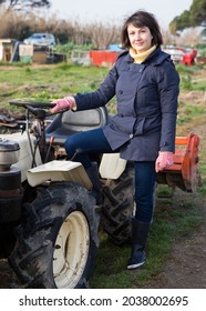 Positive Woman Working On Small Farm Tractor. High Quality Photo