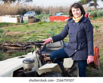 Positive Woman Working On Small Farm Tractor. High Quality Photo