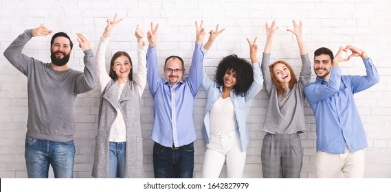 Positive Work Environment. Portrait Of Diverse Happy People Showing Funny Gestures While Posing Together Over White Brick Wall Background, Panorama