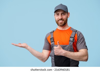 Positive worker man stands on blue background points his finger up and to side in empty place - Shutterstock ID 2163960181