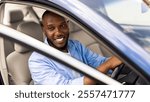 Positive young African American guy driving car and looking through open automobile door, parking or searching for fellow traveler passenger. Auto test drive, leasing, buying, rental concept