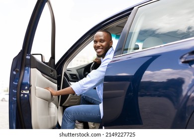 Positive Young African American Guy Going Out The Car, Looking For Fellow Traveler. Happy Black Man Open Automobile Door And Smiling, Getting In. Auto Test-drive, Leasing, Buying, Rent Concept