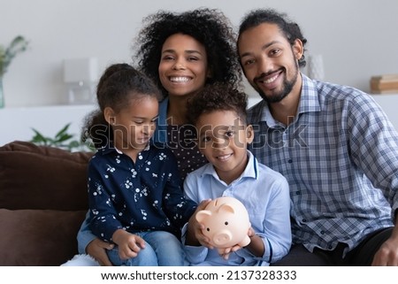 Positive young African parents and little kids showing piggybank with cash, saving money in moneybox, making donation fund, financial reserve for crisis. Happy family bank customers concept