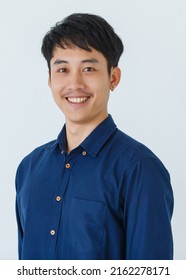Positive young Asian guy in blue shirt crossing arms and looking at camera with friendly smile against gray background - Shutterstock ID 2162278171