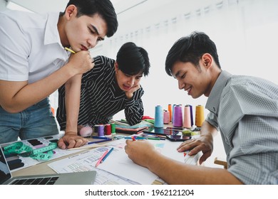 Positive young Asian men smiling and discussing together while gathering around table and creating sketches in atelier - Shutterstock ID 1962121204