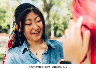 Positive Young Asian Woman With Dyed Hair Smiling Talking To Her Friend In The Park On A Sunny Day