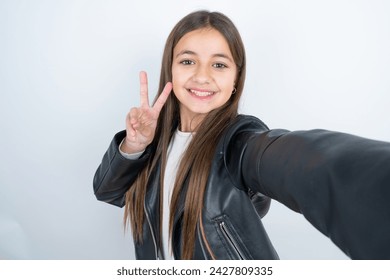 Positive Young beautiful teen girl wearing biker jacket take selfie make v-sign